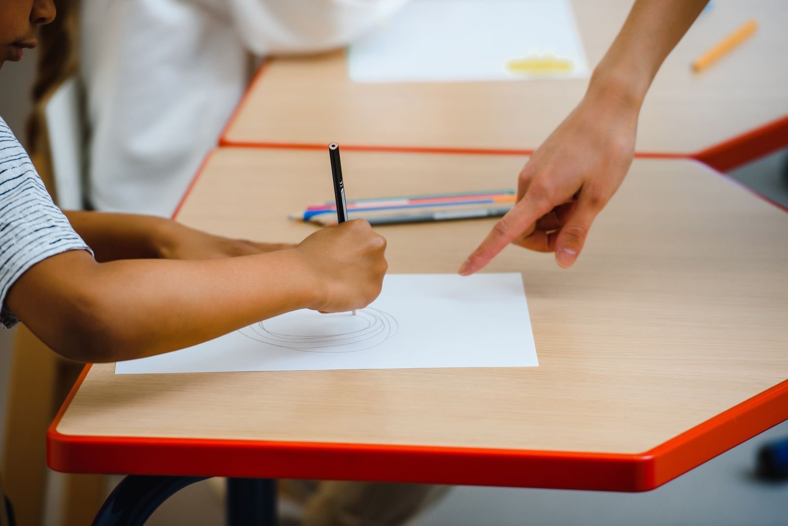 Child receiving drawing guidance from a teacher
