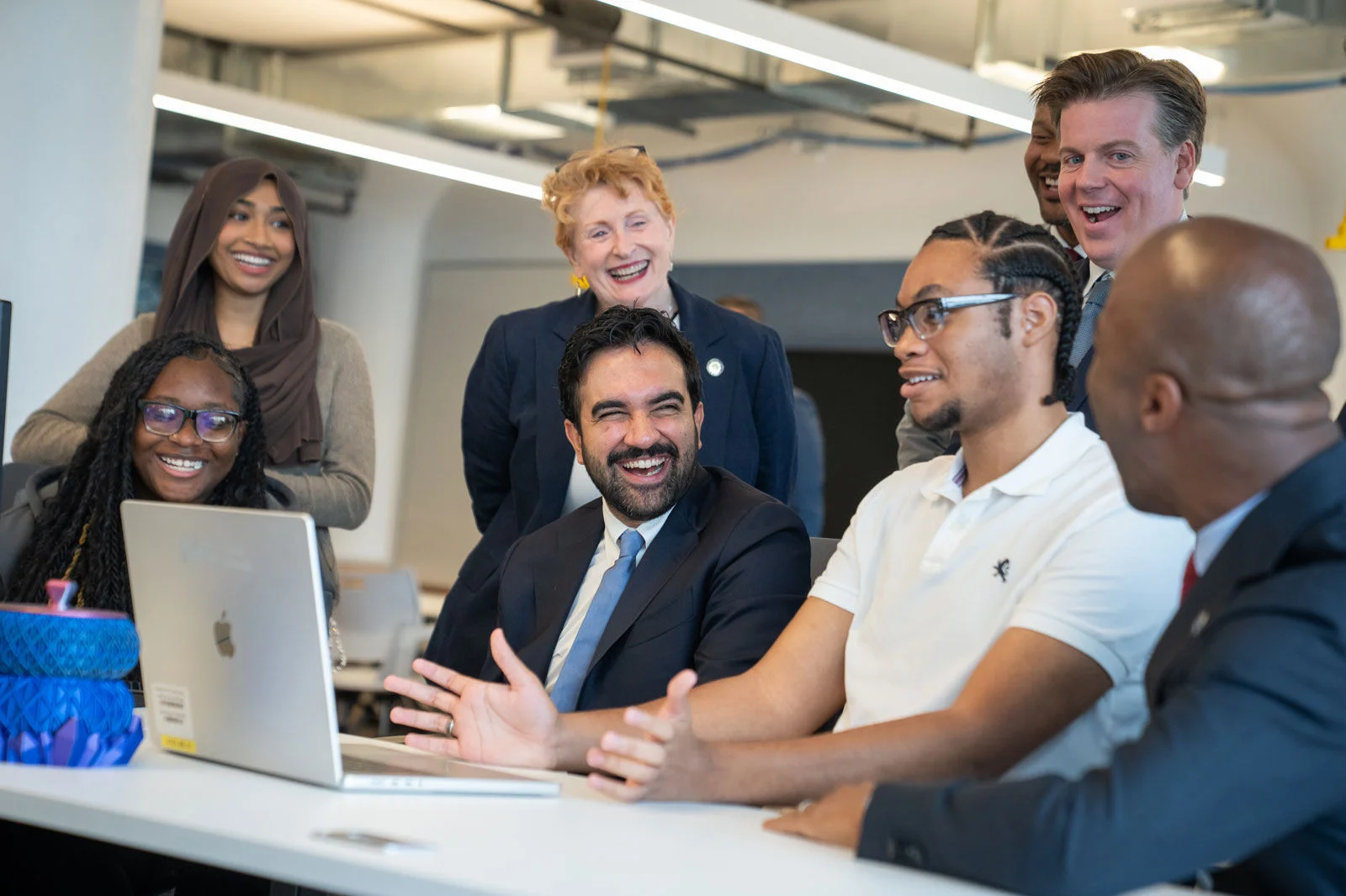 New York City officials and educators gathered around a student using a laptop